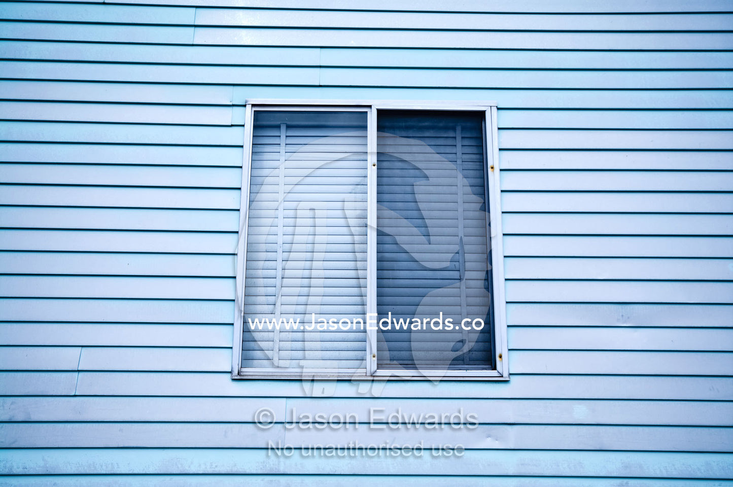 An old blue weatherboard timber wall and shuttered window of a house. Fitzroy North, Victoria, Australia