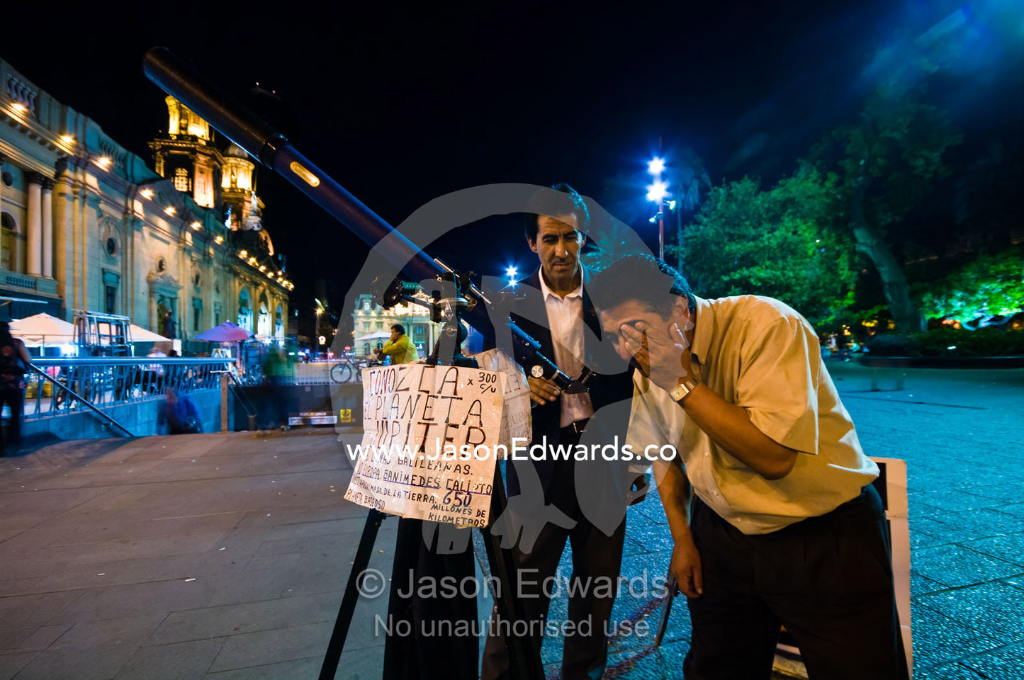An astronomer teachers a tourist about Jupiter through a telescope. Plaza de Armas, Santiago, Chile