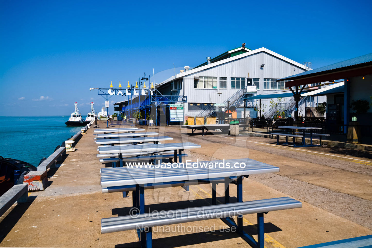 Picnic tables line a marina where tourists dine and and relax. Darwin Waterfront, Darwin, Northern Territory, Australia