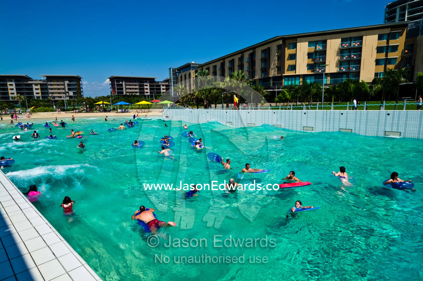 Tourists and residents swim in artificially generated waves in a pool. Wave Lagoon, Darwin, Northern Territory, Australia
