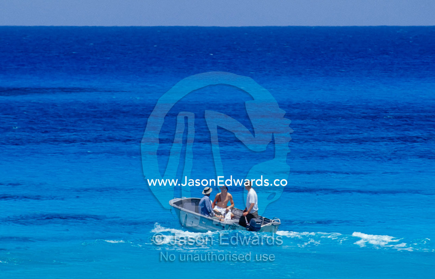 A group of men on a tropical turquoise ocean in an aluminium dingy. Coral Sea, Queensland, Australia