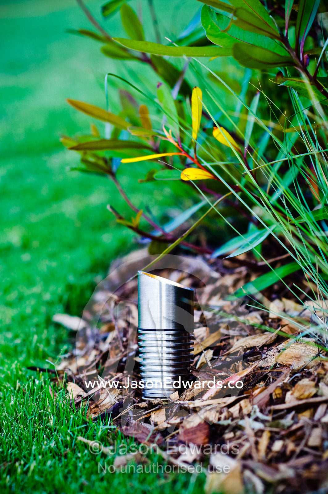 A stainless steel lighting fixture illuminates a garden bed and lawn. Red Hill, Mornington Peninsula, Victoria, Australia.
