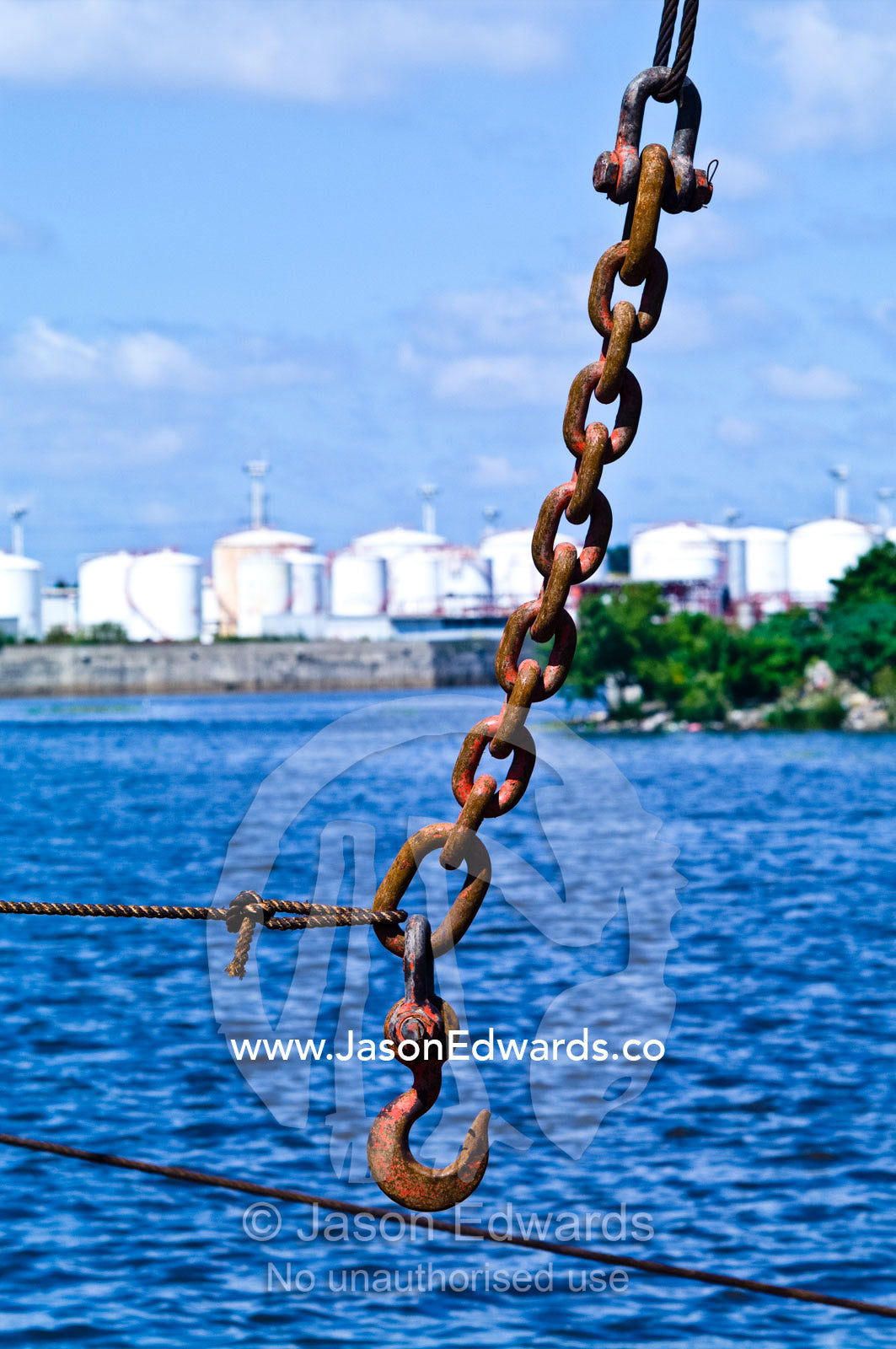 A steel cable holds a chain and hook from a crane above a river port. La Riachuelo, Little River, La Boca, Buenos Aires, Argentina.