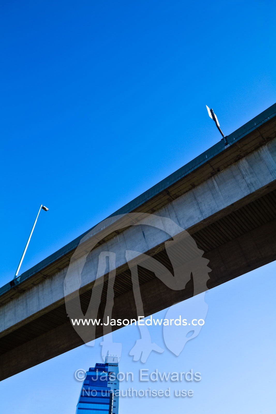 A concrete freeway overpass straddles a glass business office tower. Puerto Madero, Buenos Aires, Argentina.