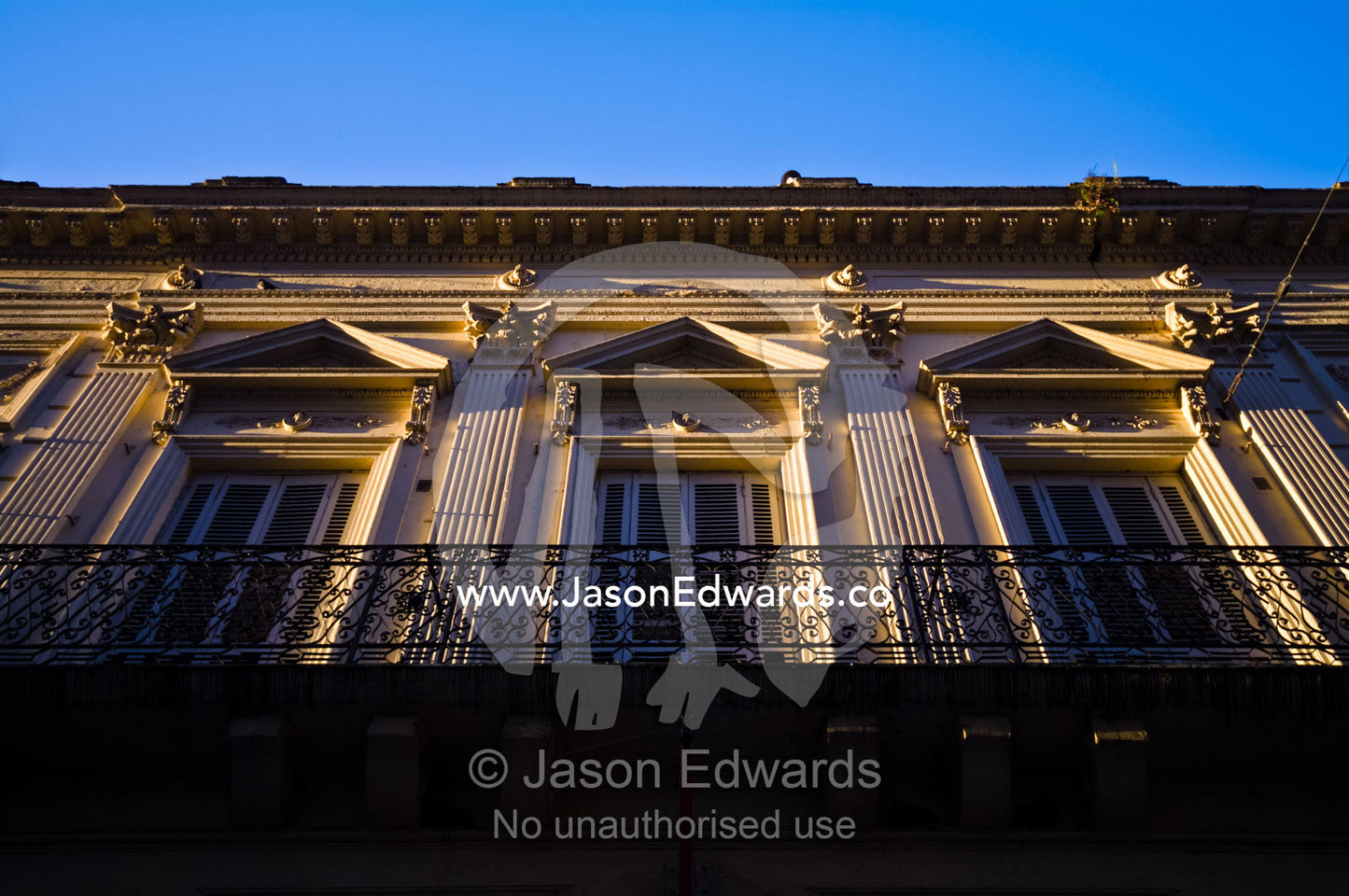 An ornate cast iron balcony and shuttered Neoclassical windows. San Telmo, Buenos Aires, Argentina.