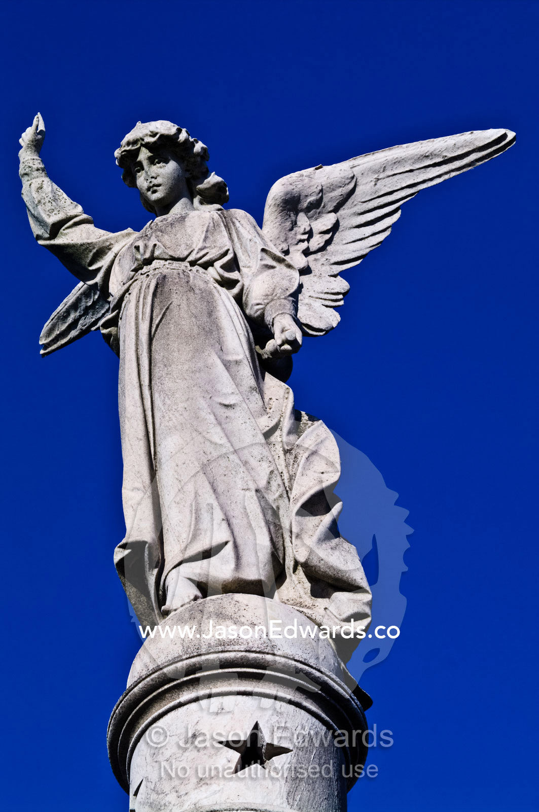A concrete statue of an angel on the roof of a family mausoleum. La Recoleta Cemetery, Recoleta, Buenos Aires, Argentina.