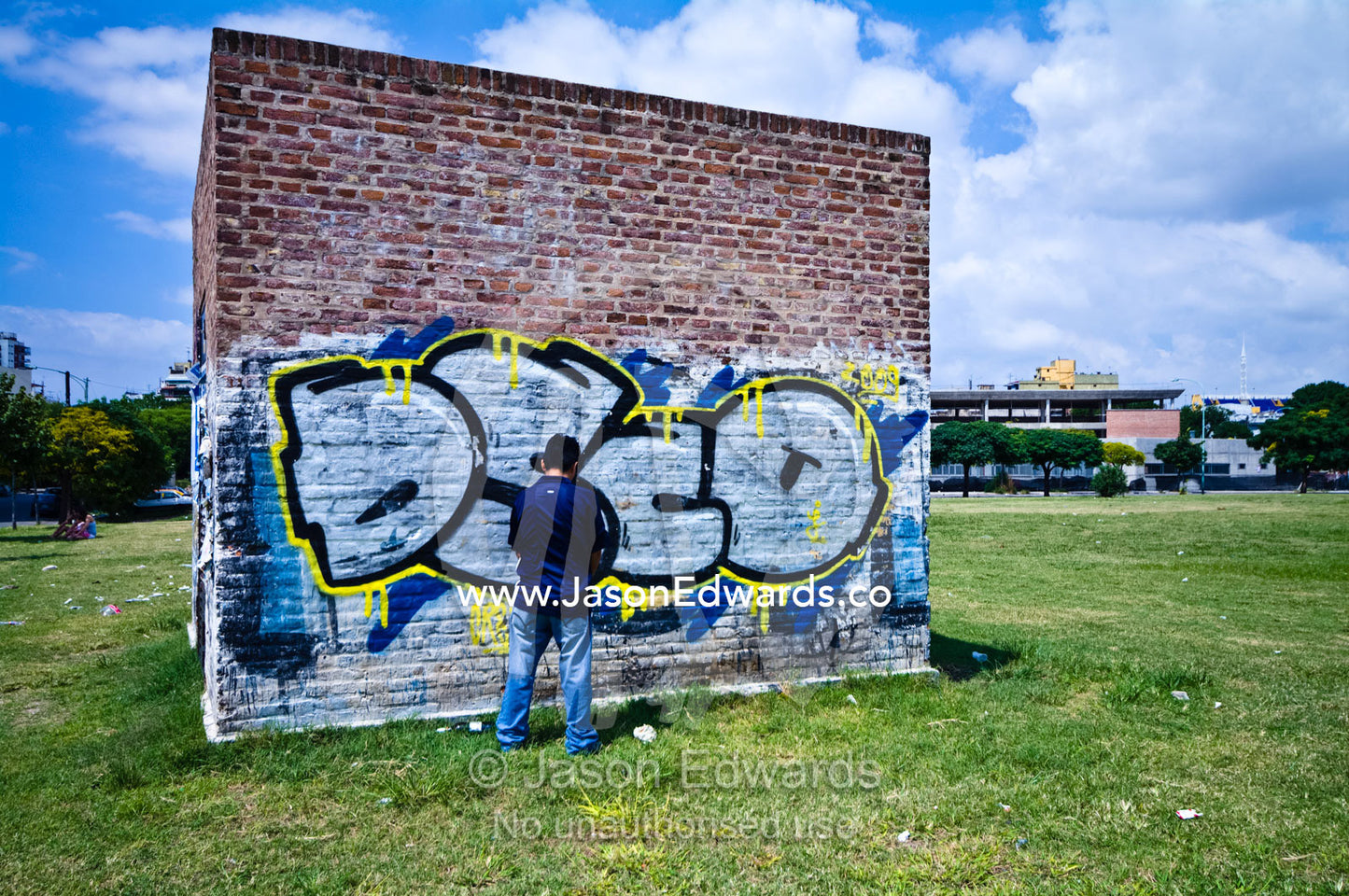 A teenage boy urinates on graffiti covered wall by a football field. La Boca, Buenos Aires, Argentina.