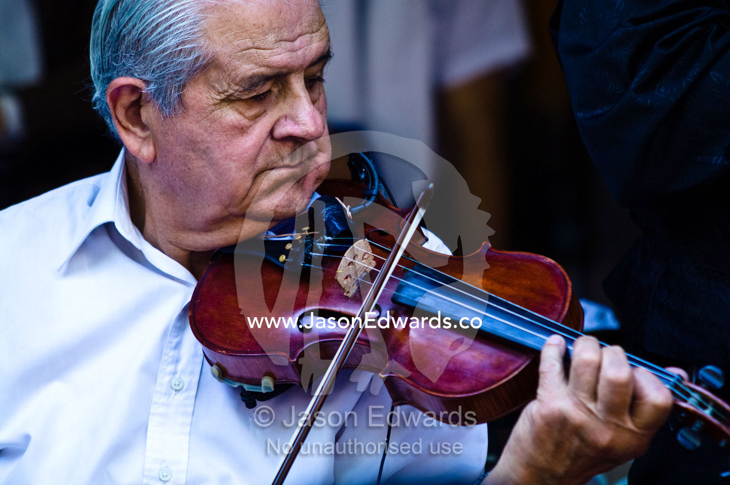 An elderly musician plays a violin creating rhythm for Tango dancers. El Caminito, La Boca, Buenos Aires, Argentina.