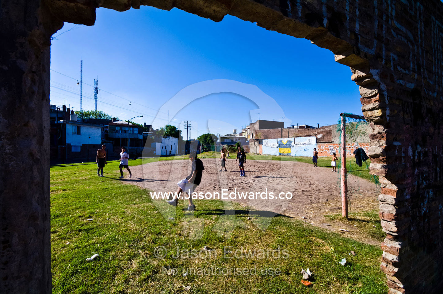 Boys play football on vacant land surrounded by crumbling brick walls. La Boca, Buenos Aires, Argentina.