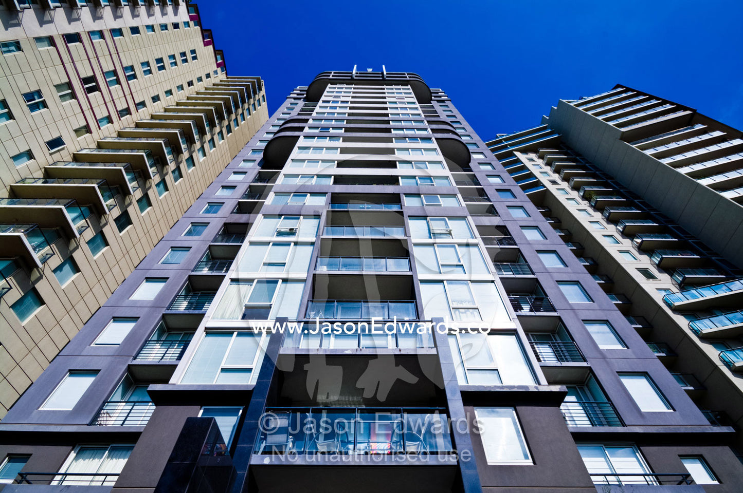 An inner city apartment complex facade towers into a clear blue sky. St Kilda Road, Melbourne, Victoria, Australia.