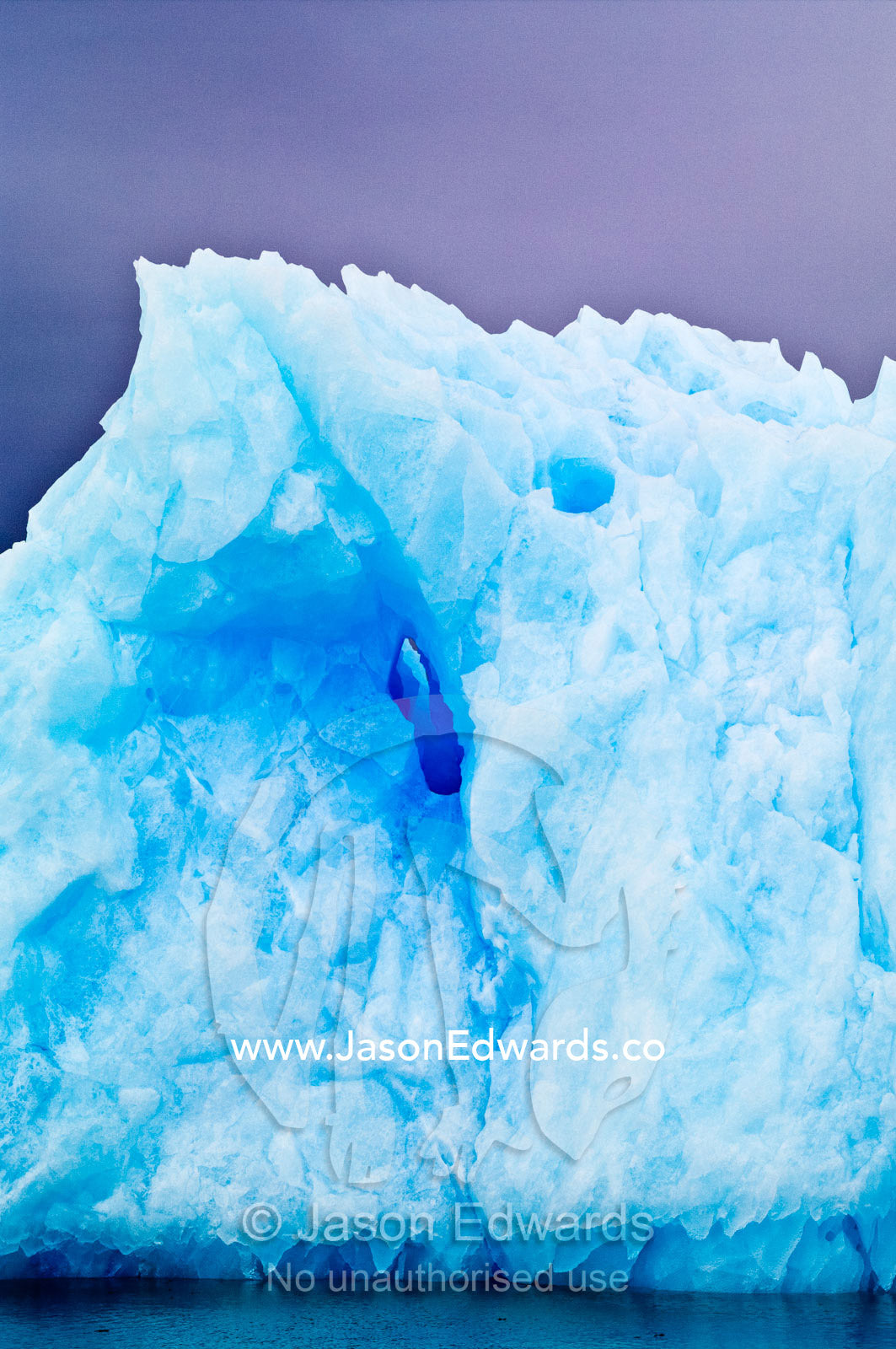 Razor serrations on the edge of an iridescent blue iceberg. Fish Islands, Flouder Island, The Minnows, Crystal Sound, Antarctic Peninsula, Antarctic Circle, Antarctica.