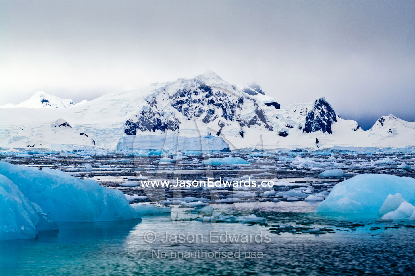 Crushed ice and fractured icebergs on a sea beneath a mountain range. Fish Islands, Flouder Island, The Minnows, Crystal Sound, Antarctic Peninsula, Antarctic Circle, Antarctica.