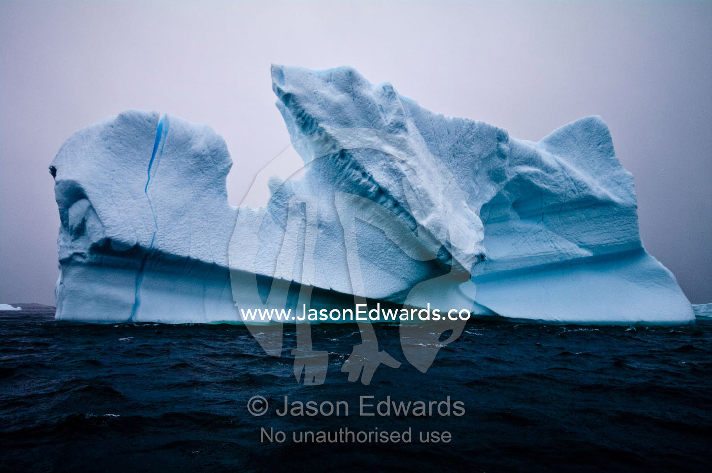 Jagged icebergs rise from a deep dark sea beneath a bitter grey sky. Pl��neau and Booth Islands, Bellingshausen Sea, Antarctic Peninsula, Antarctica.