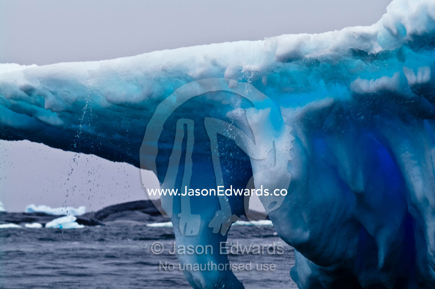 Rain and ice melt pour from the lip of a sculptured iceberg. Pl��neau and Booth Islands, Bellingshausen Sea, Antarctic Peninsula, Antarctica.