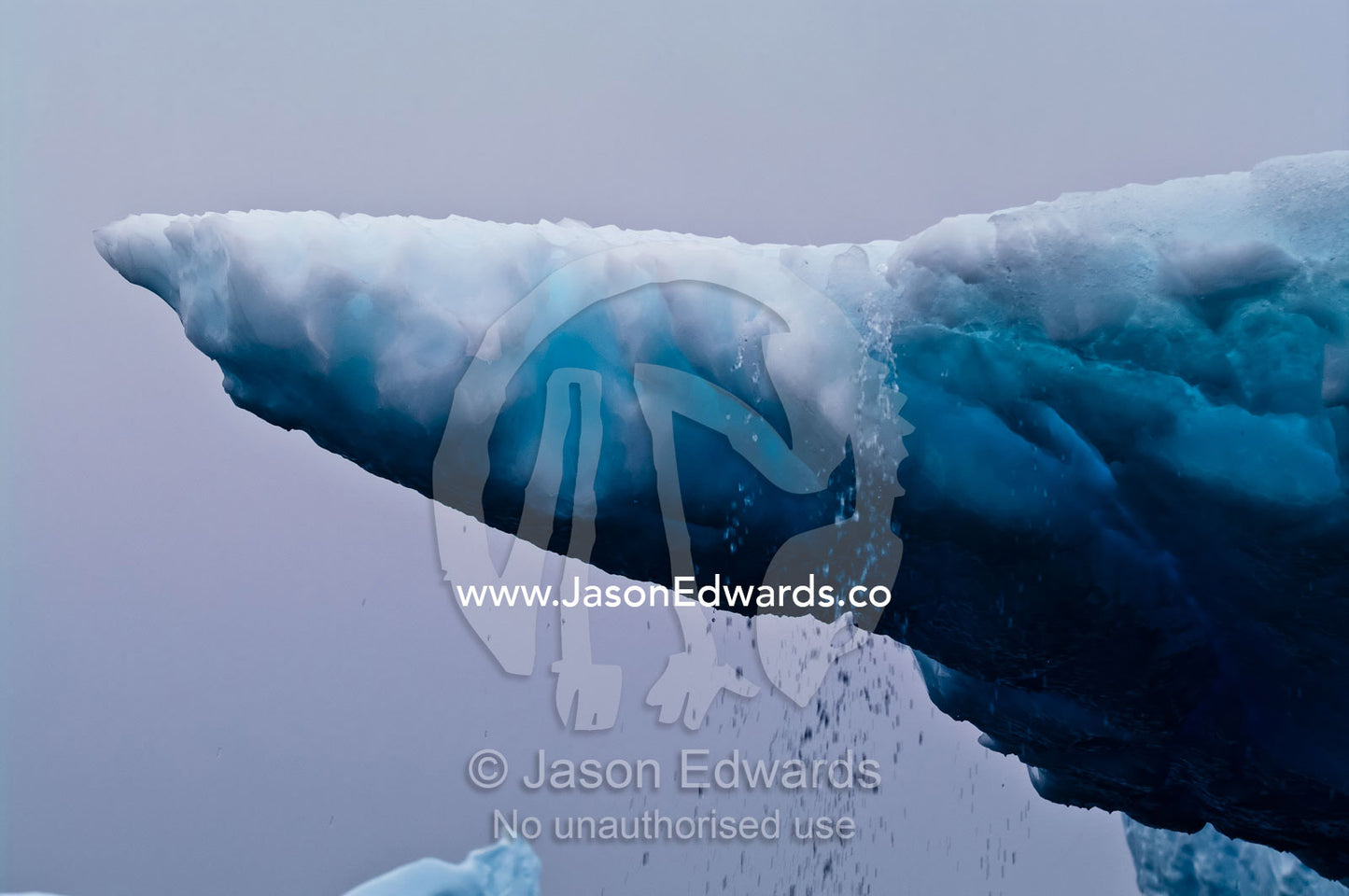 Rain and ice melt pour from the lip of a sculptured iceberg. Pl��neau and Booth Islands, Bellingshausen Sea, Antarctic Peninsula, Antarctica.