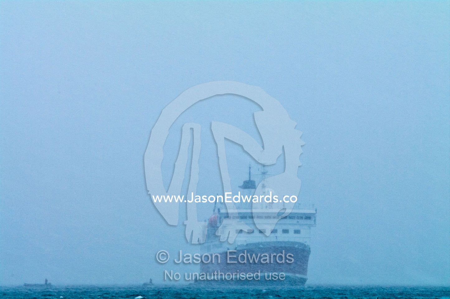 Small inflatable zodiac boats and an ecotourism ship in a blizzard. Danco Island, Antarctic Peninsula, Antarctica.