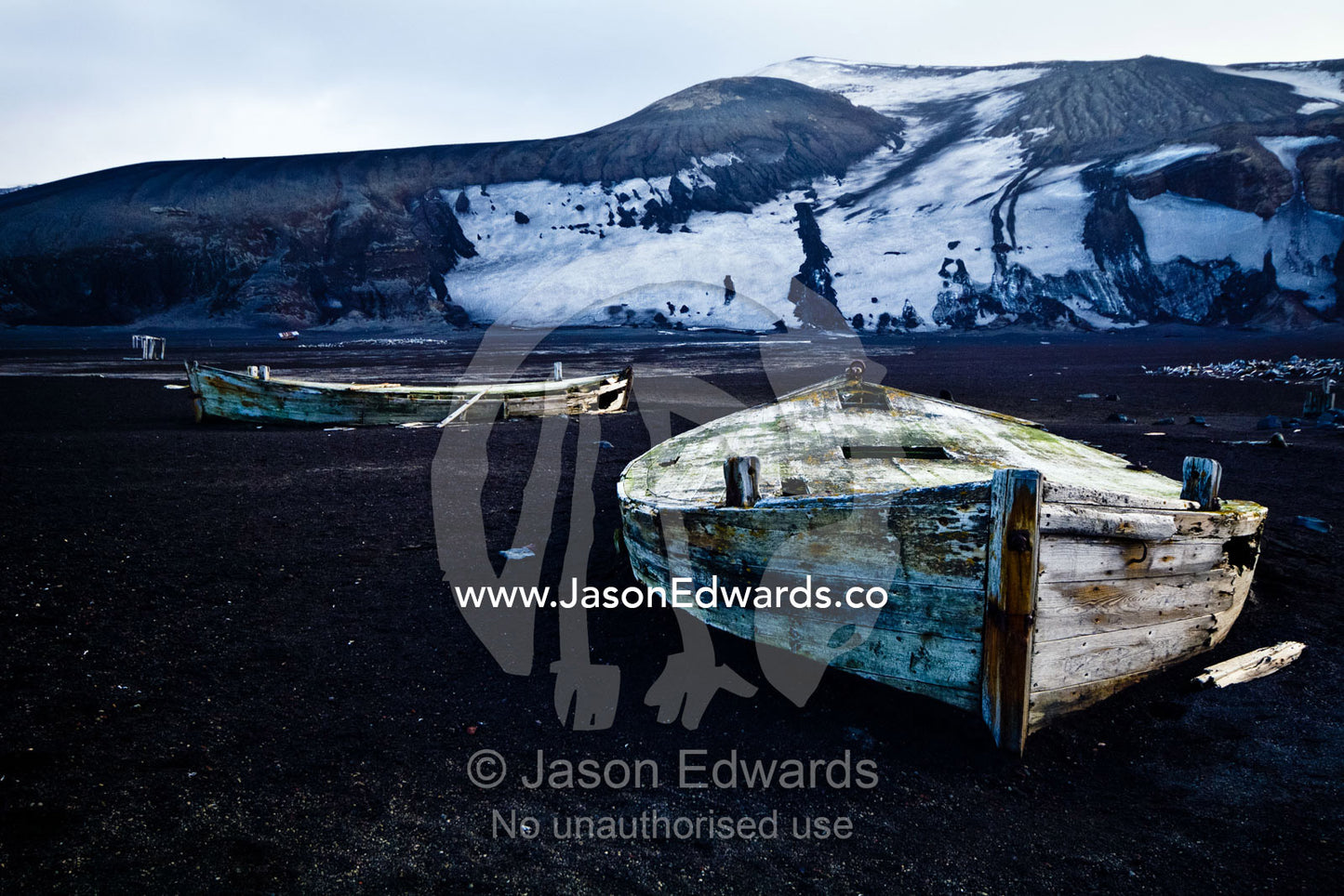Antique timber whaling boat ruins stranded in black volcanic sand. Hektor Whaling Station, Whalers Bay, Port Foster, Deception Island, South Shetland Islands, Antarctic Peninsula, Antarctica.