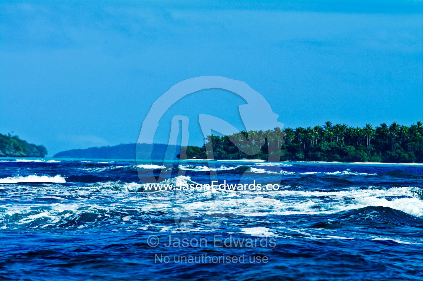 The incoming tide rushes over a coral reef between tropical islands. Vava'u Island Group, Pacific Ocean, Oceania, Kingdom of Tonga.