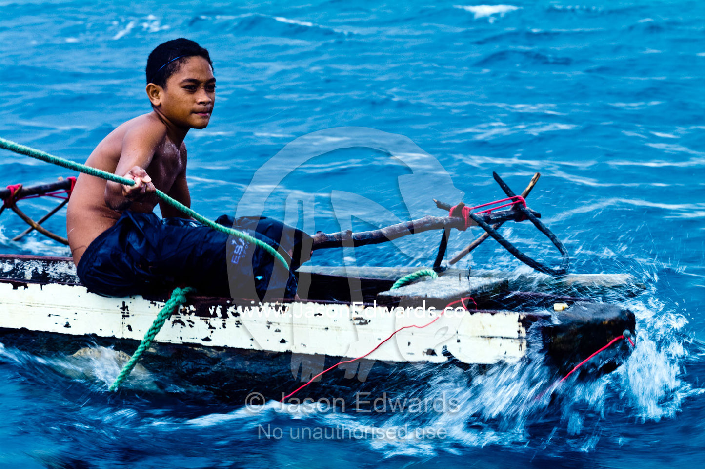 A young boy is towed to safety from a storm in an outrigger canoe. Vava'u Island Group, Pacific Ocean, Oceania, Kingdom of Tonga.