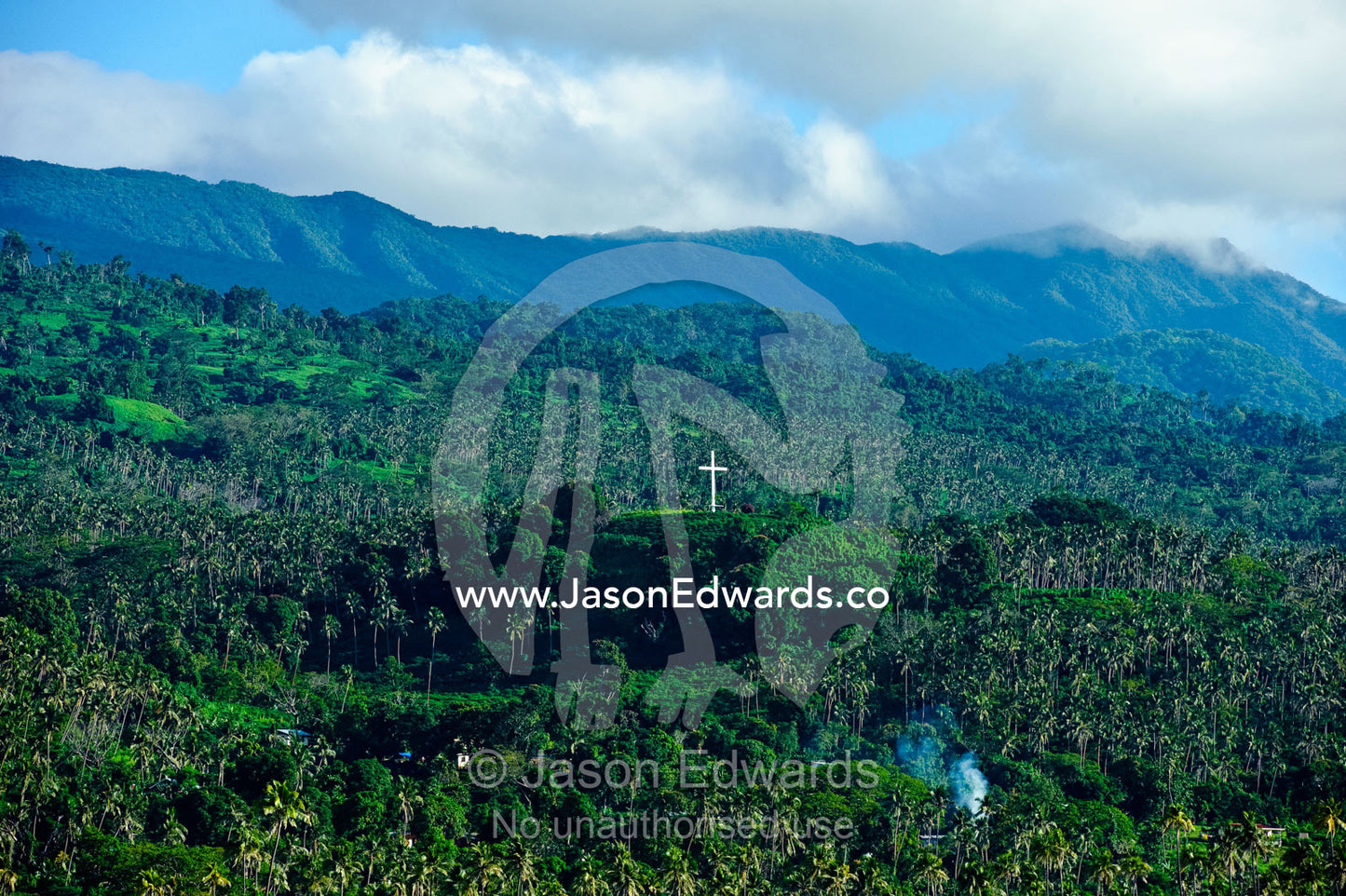 A crucifix on a lush hillside surrounded by palm tree plantations. Taveuni Island, Pacific Ocean, Fiji Islands.