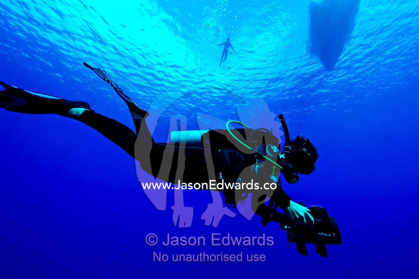 A scuba diver descends from a boat into the deep with a video camera. Kokod Point, Ringgold Atolls, Pacific Ocean, Fiji Islands.