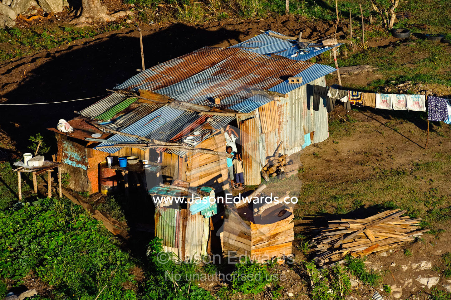 A farming family waves from their corrugated tin home to a balloon. Viti Levu, Pacific Ocean, Fiji Islands.