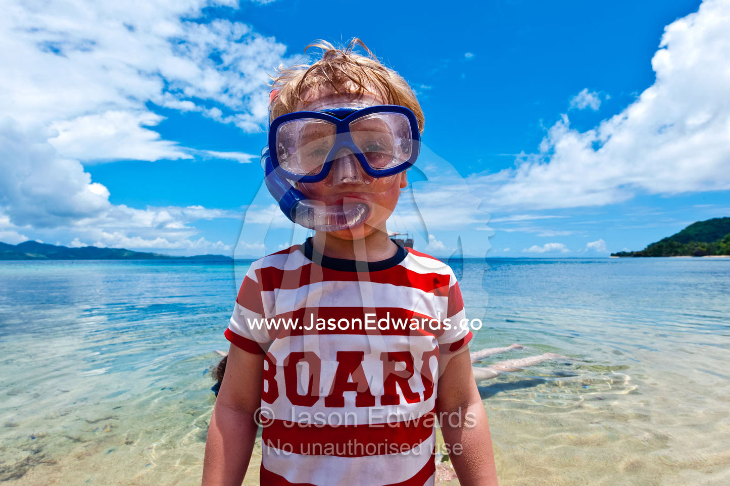A boy wears his snorkel and mask in the shallows of a tropical island. Rabi Island, Somosomo Strait, Pacific Ocean, Fiji Islands.