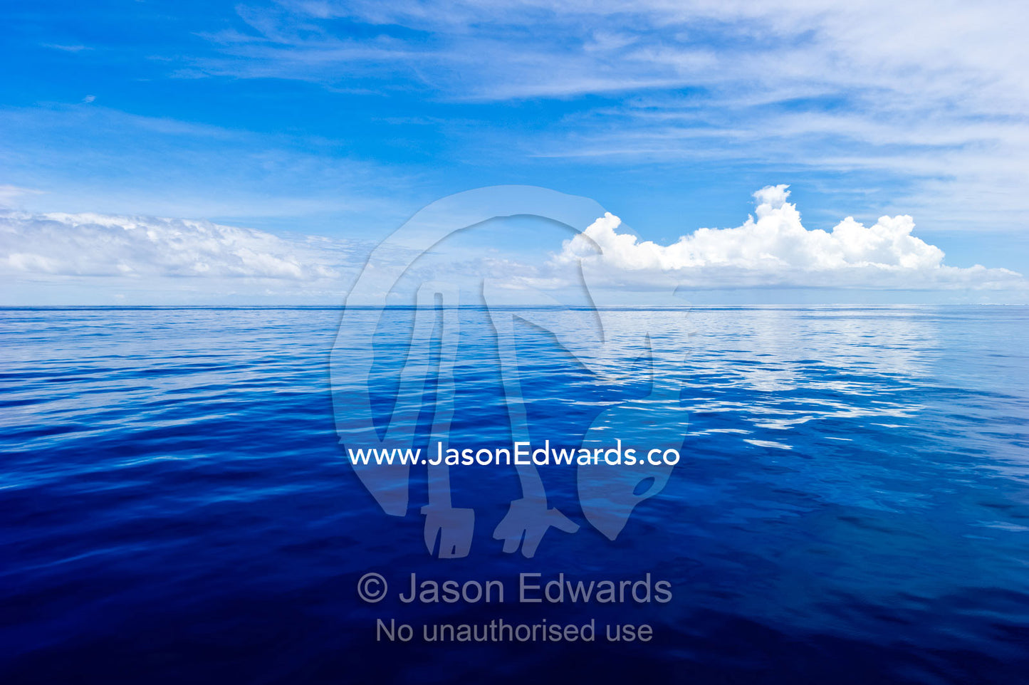 Clouds hovering over a deep blue dead calm tropical sea. Tavarua Island, Malolo Archipelago, Pacific Ocean, Fiji Islands.