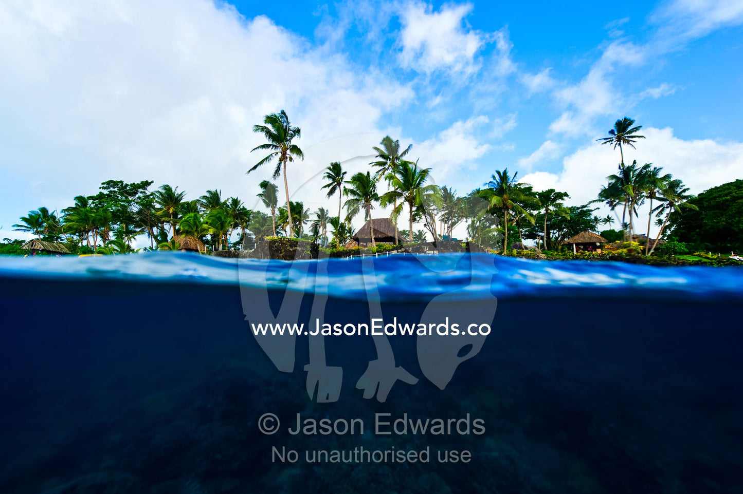 A coral reef lines the shore beneath a tropical island resort. Home Reef, Taveuni Island, Somosomo Strait, Pacific Ocean, Fiji Islands.