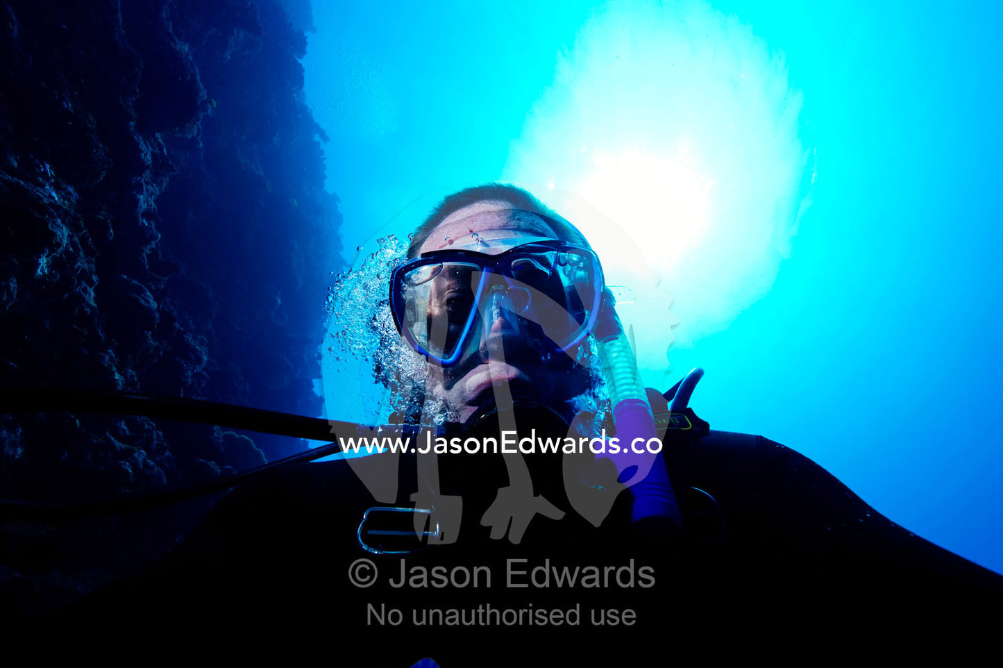 A scuba diver exhales as he descends down a reef wall into the abyss. Kokod Point, Ringgold Atolls, Pacific Ocean, Fiji Islands.