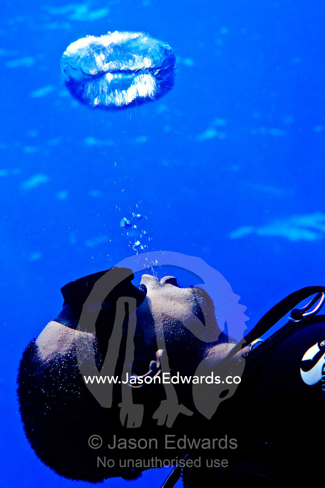 A scuba diver exhales bubbles rings that float towards the surface. Kokod Point, Ringgold Atolls, Pacific Ocean, Fiji Islands.