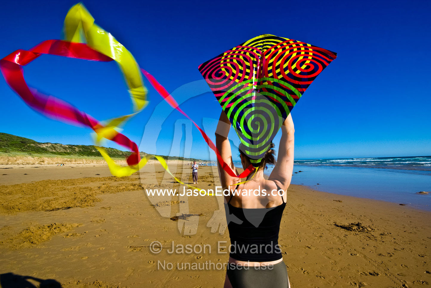 A woman prepares to launch a kite on a windswept beach during summer. Cape Liptrap Coastal Park, Venus Bay, Bass Strait, South Gippsland, Victoria, Australia.