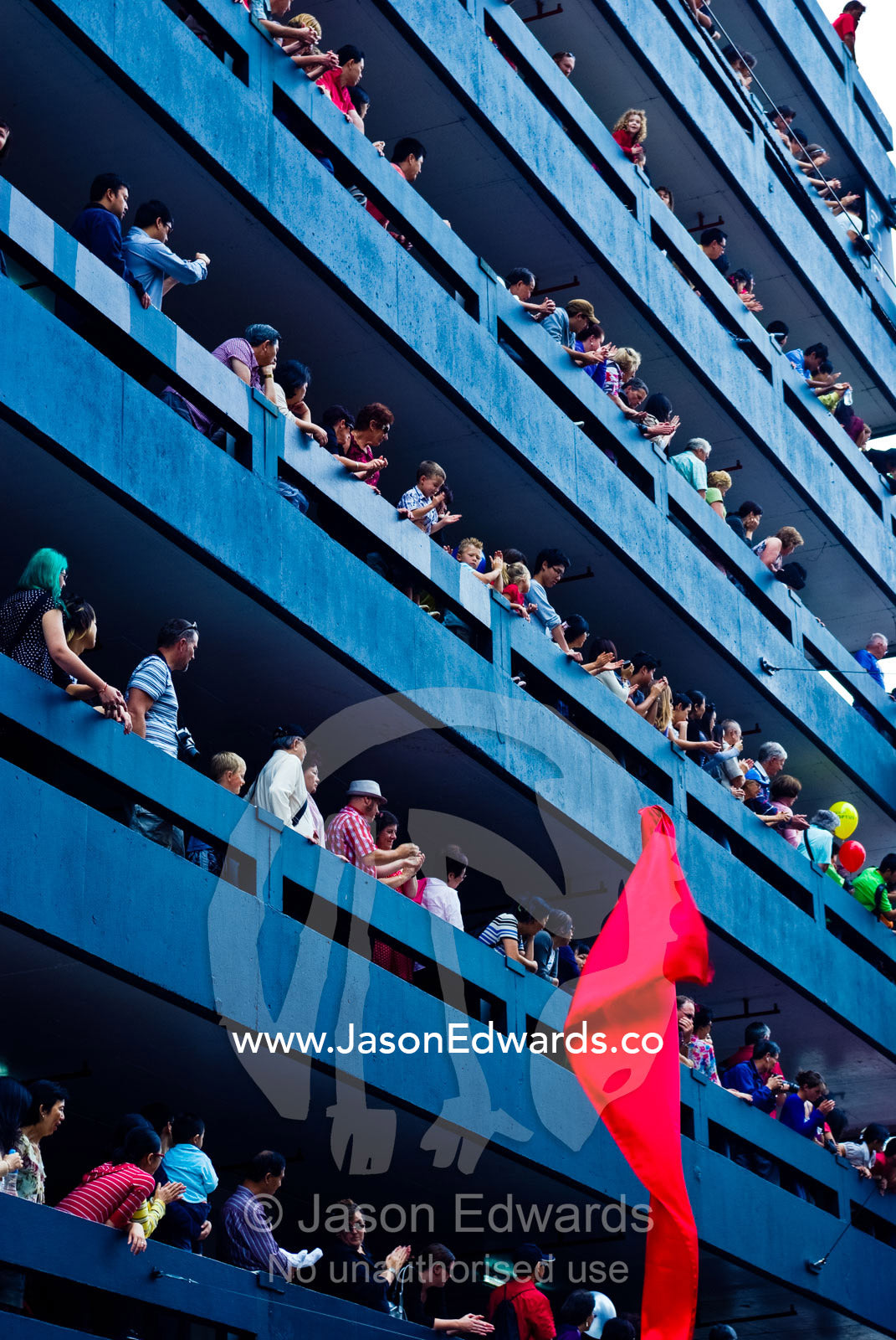 Crowds gather balconies on a high-rise car park to watch a parade. Melbourne, Victoria, Australia.