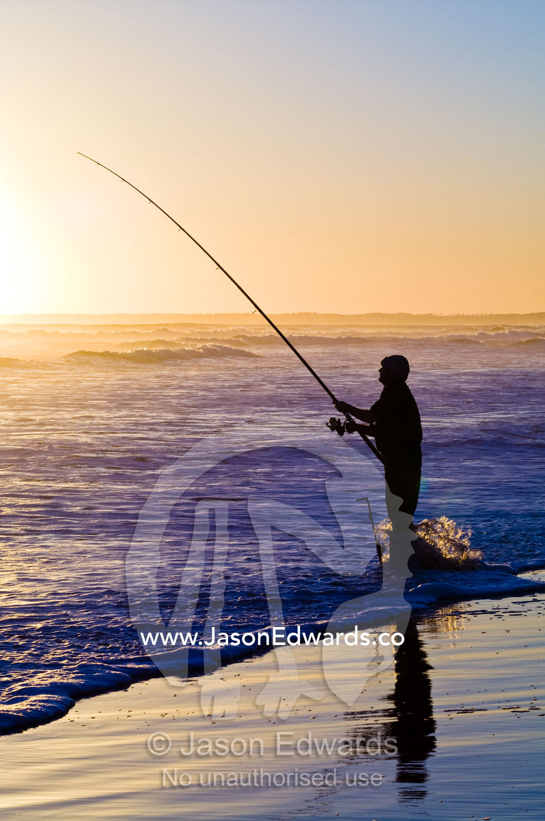 Fishermen try to hook a fish in the waves with long surf fishing rods. Venus Bay, Bass Strait, South Gippsland, Victoria, Australia.