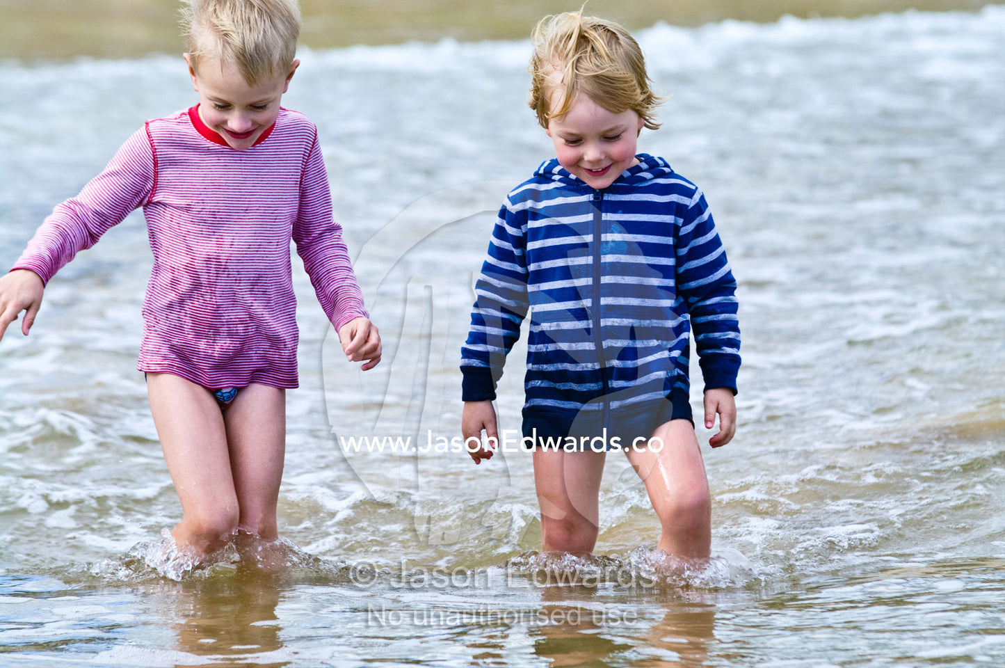 Two young friends playing in the shallows and waves at the beach. Venus Bay, Bass Strait, South Gippsland, Victoria, Australia.