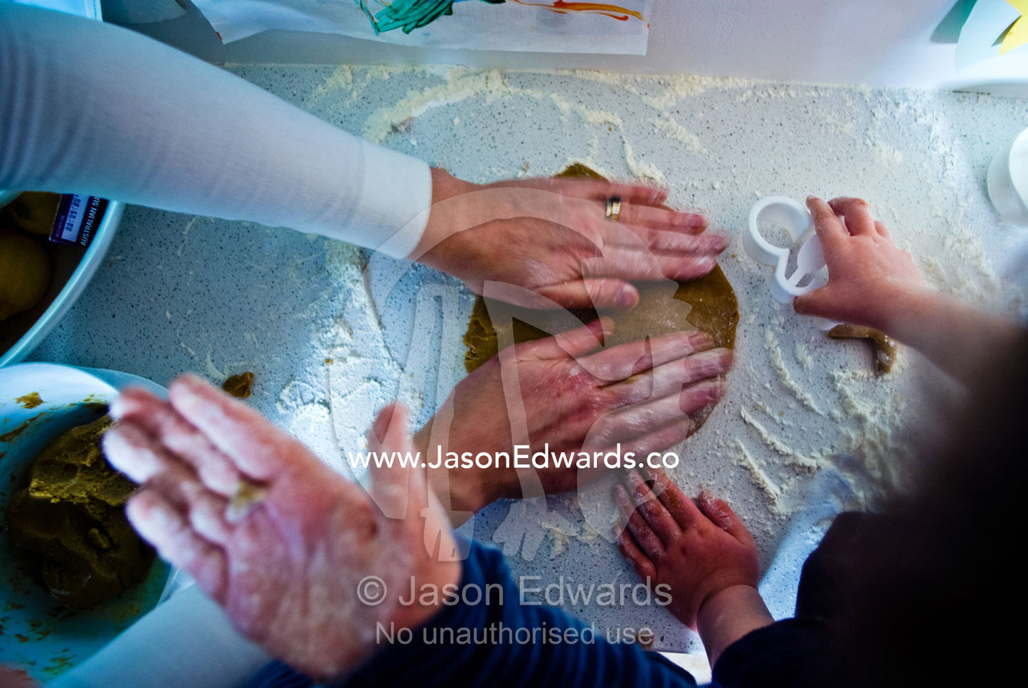 A mother helps children bake gingerbread on a kitchen bench with flour Carlton North, Melbourne, Victoria, Australia.