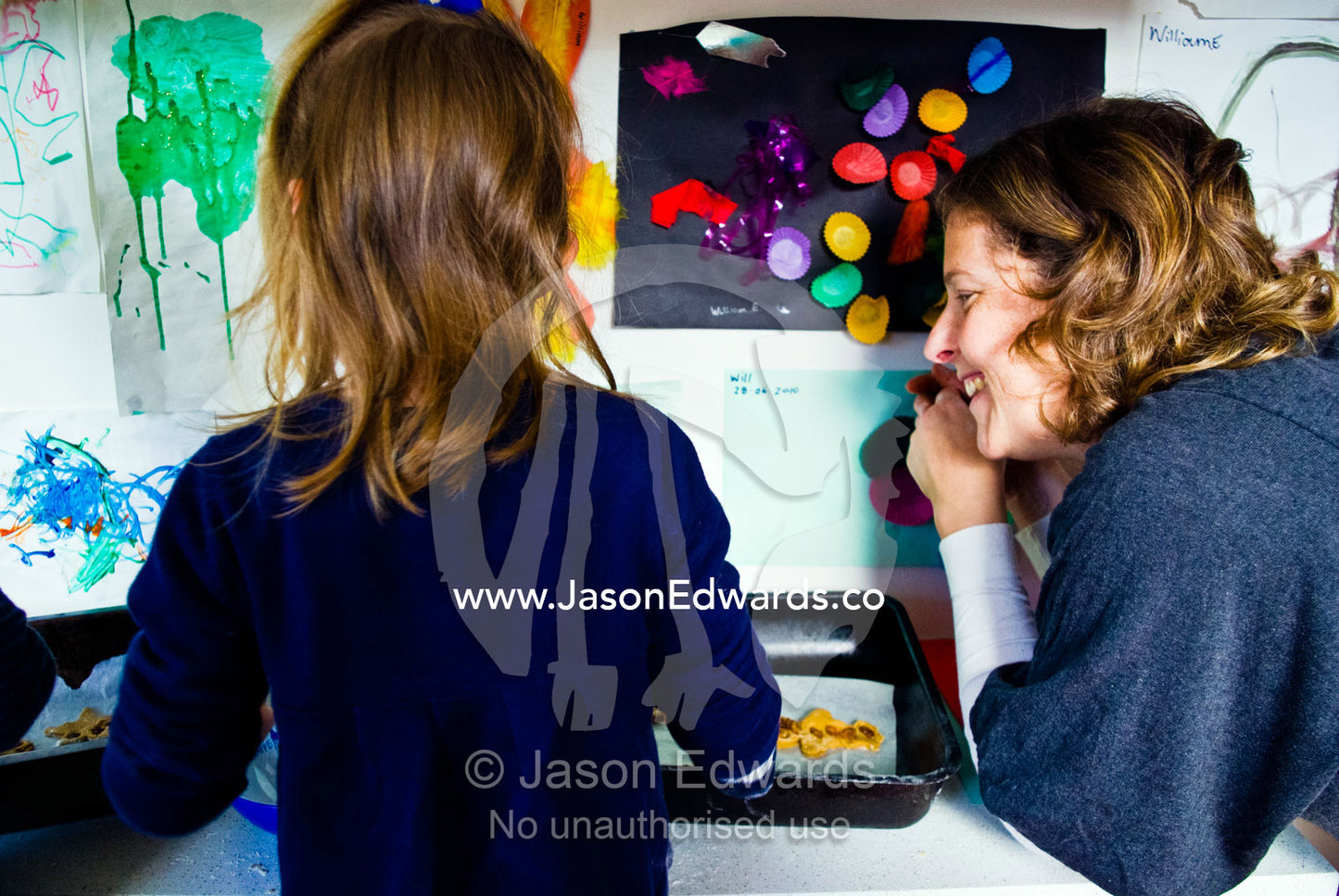 A mother helps children bake gingerbread men in a domestic kitchen. Carlton North, Melbourne, Victoria, Australia.