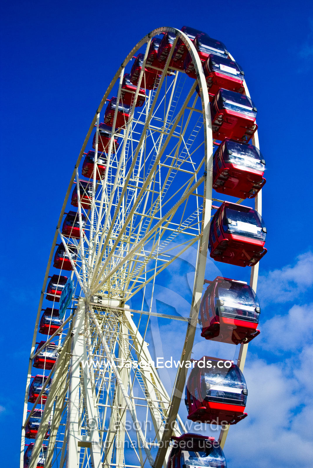 A bright red ferris gondolas on a wheel rising into a clear blue sky. Royal Melbourne Show, Royal Melbourne Agricultural Show, Flemington, Victoria, Australia.