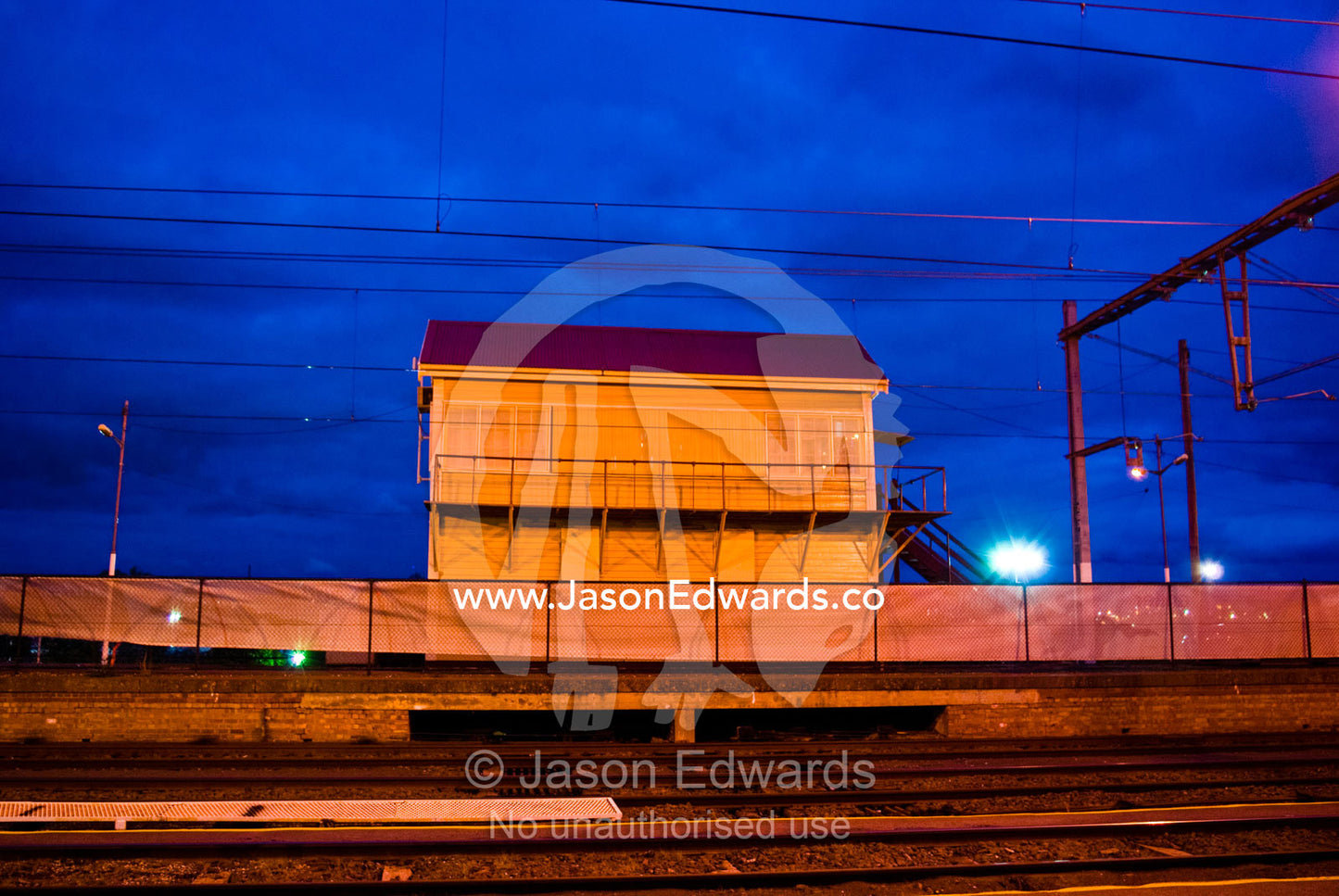 An empty railway station and tracks under flood lights late at night. Flemington, Victoria, Australia.