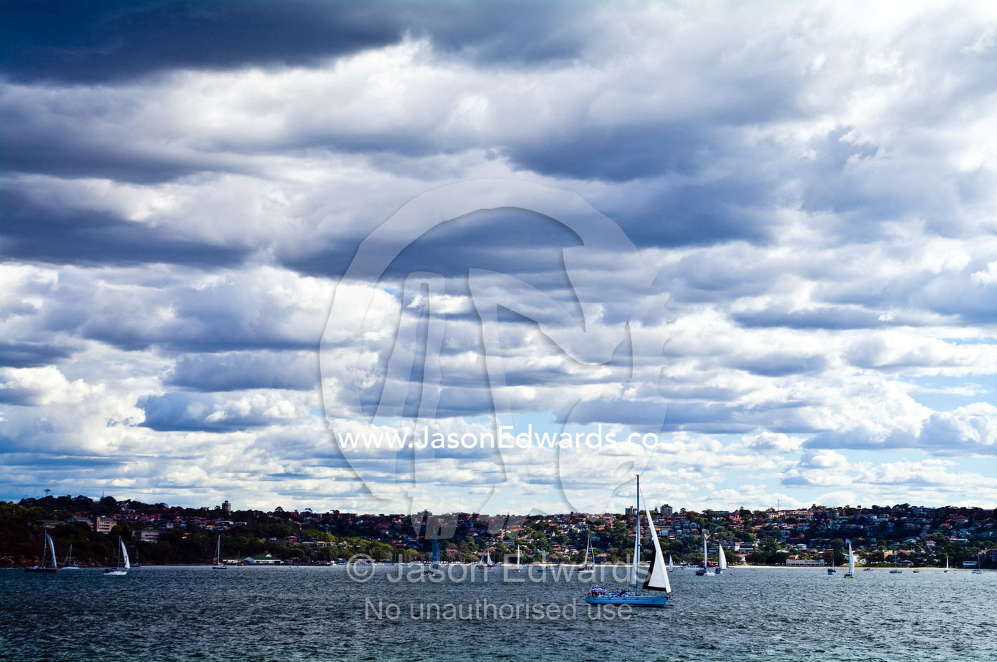 Summer storm clouds gather over racing yachts sailing in a regatta. Manly Cove, Manly, Sydney Harbour, Sydney, New South Wales, Australia.