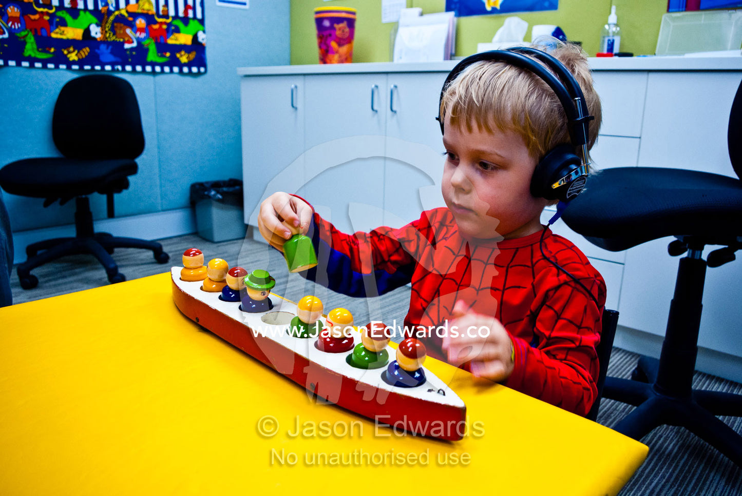 A boy undergoes a clinical hearing test using headphones and toys. Carlton, Melbourne, Victoria, Australia.