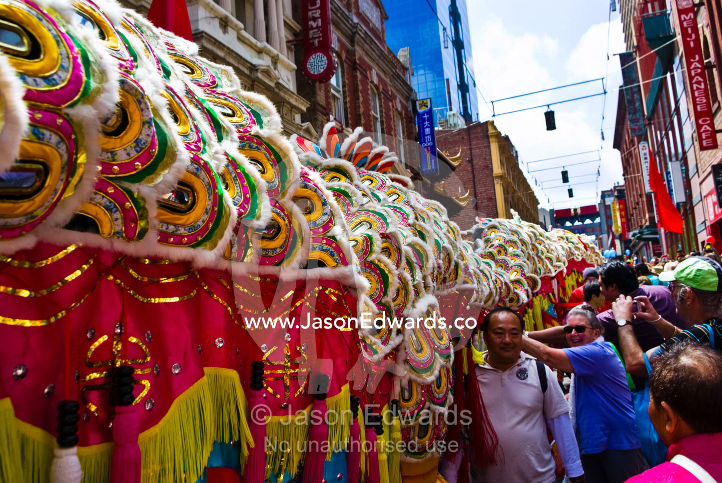 Crowds touch a ceremonial dragon for good luck at Chinese New Year. Chinatown, Melbourne, Victoria, Australia.