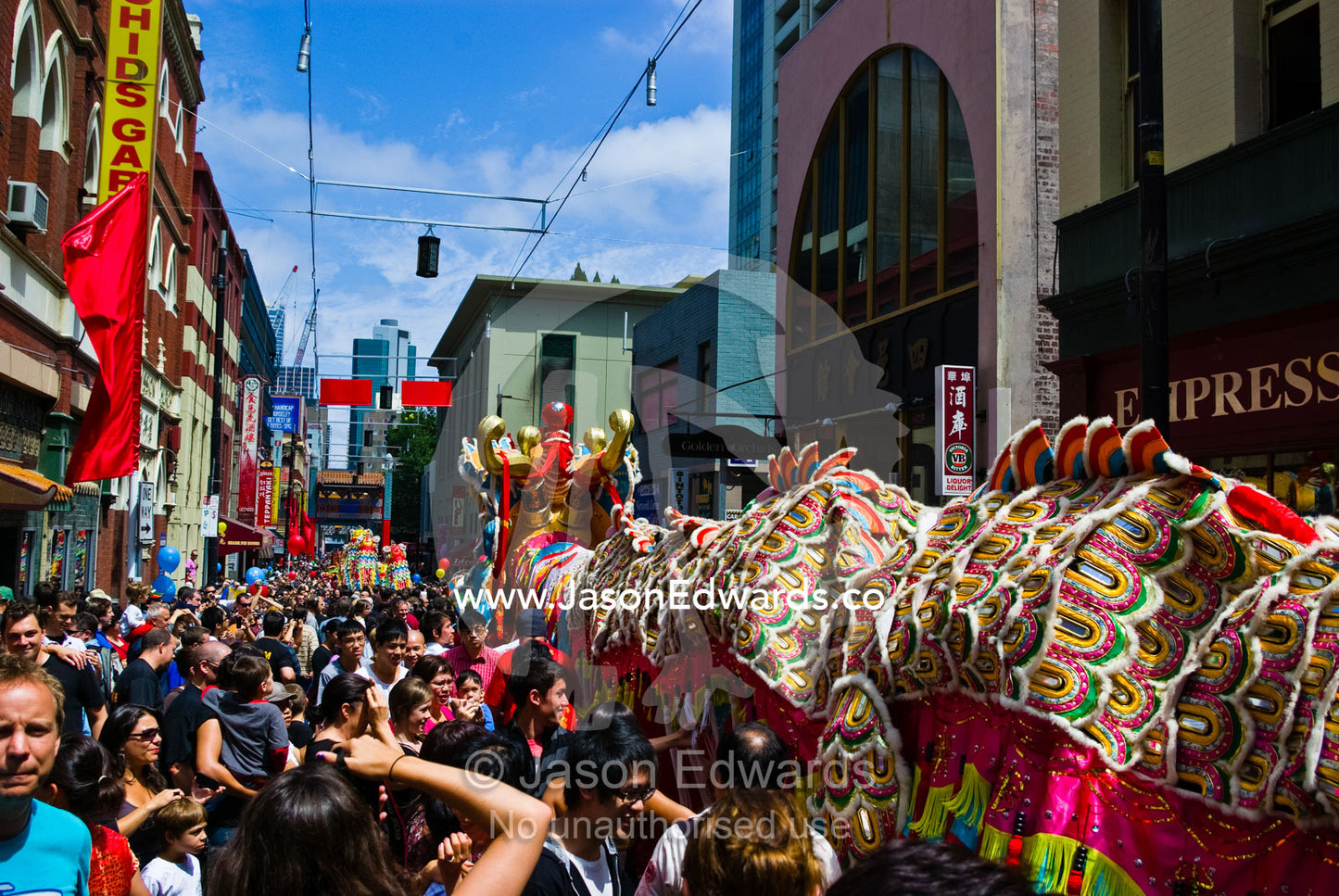 Crowds touch a ceremonial dragon for good luck at Chinese New Year. Chinatown, Melbourne, Victoria, Australia.