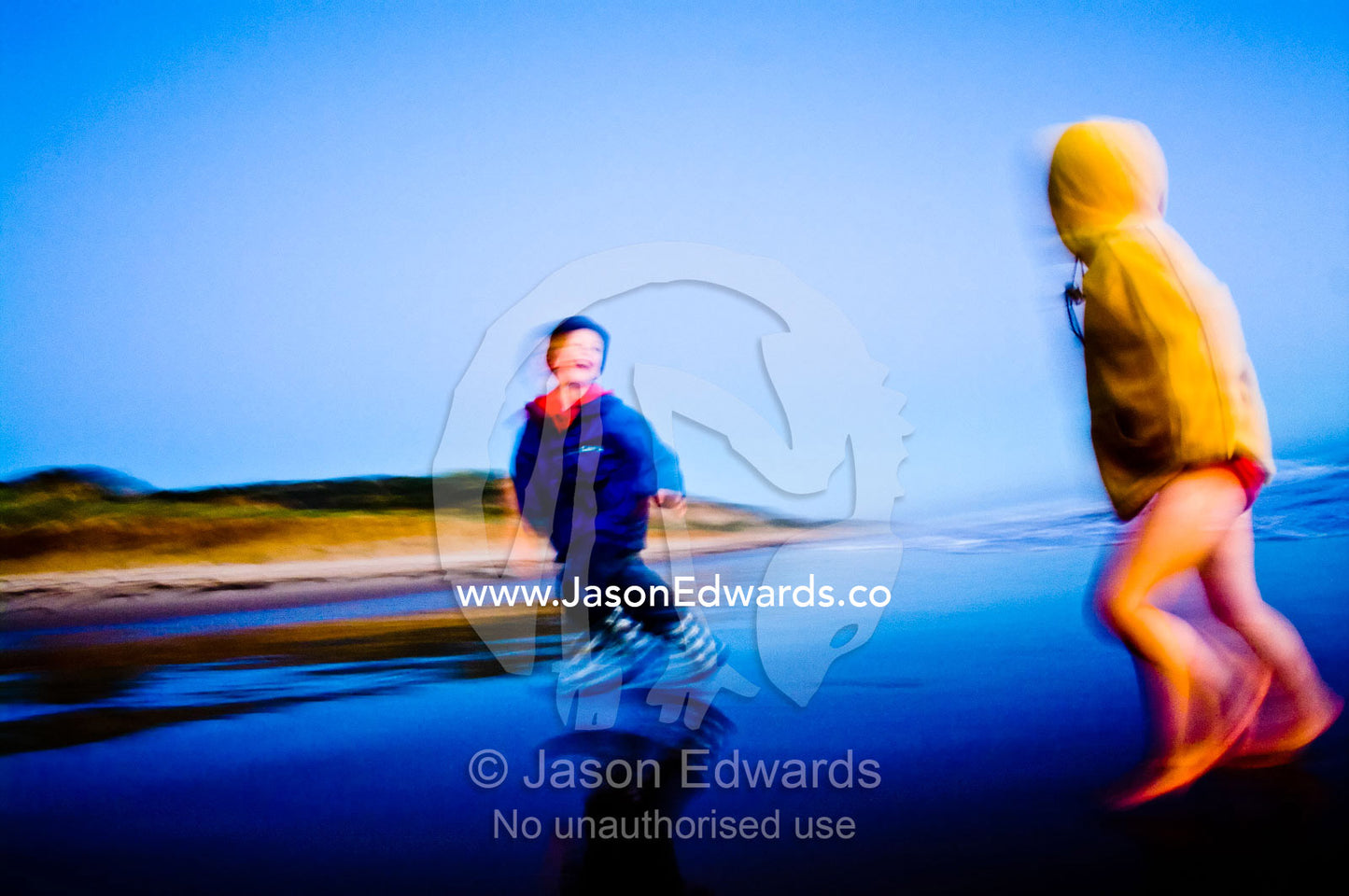 Small boys run from waves on a remote stretch of beach at twilight. Venus Bay, Cape Liptrap Coastal Park, Bass Strait, South Gippsland, Victoria, Australia.