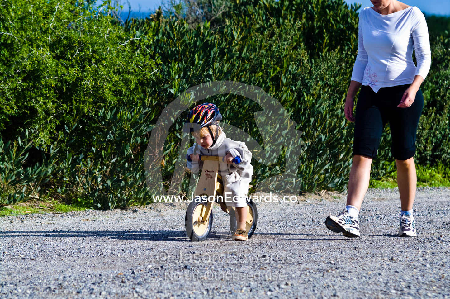 A young boy learns to ride a balance bike made from recycled timber. Venus Bay, Cape Liptrap Coastal Park, Bass Strait, South Gippsland, Victoria, Australia.