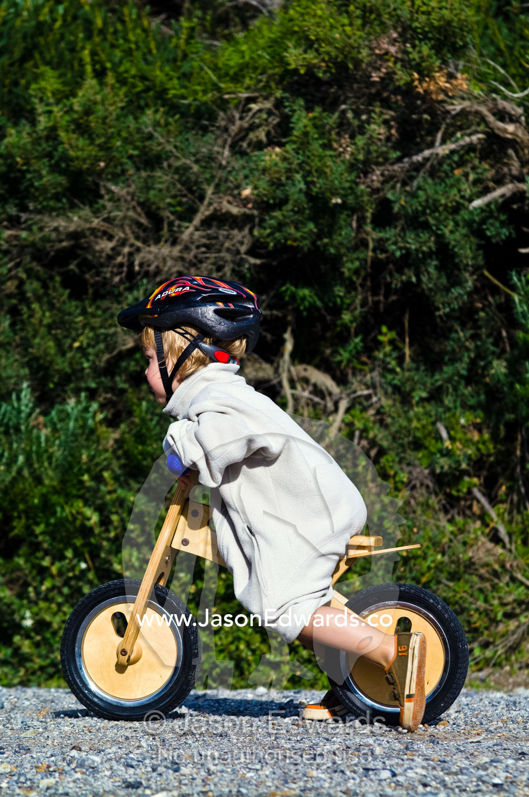 A young boy learns to ride a balance bike made from recycled timber. Venus Bay, Cape Liptrap Coastal Park, Bass Strait, South Gippsland, Victoria, Australia.