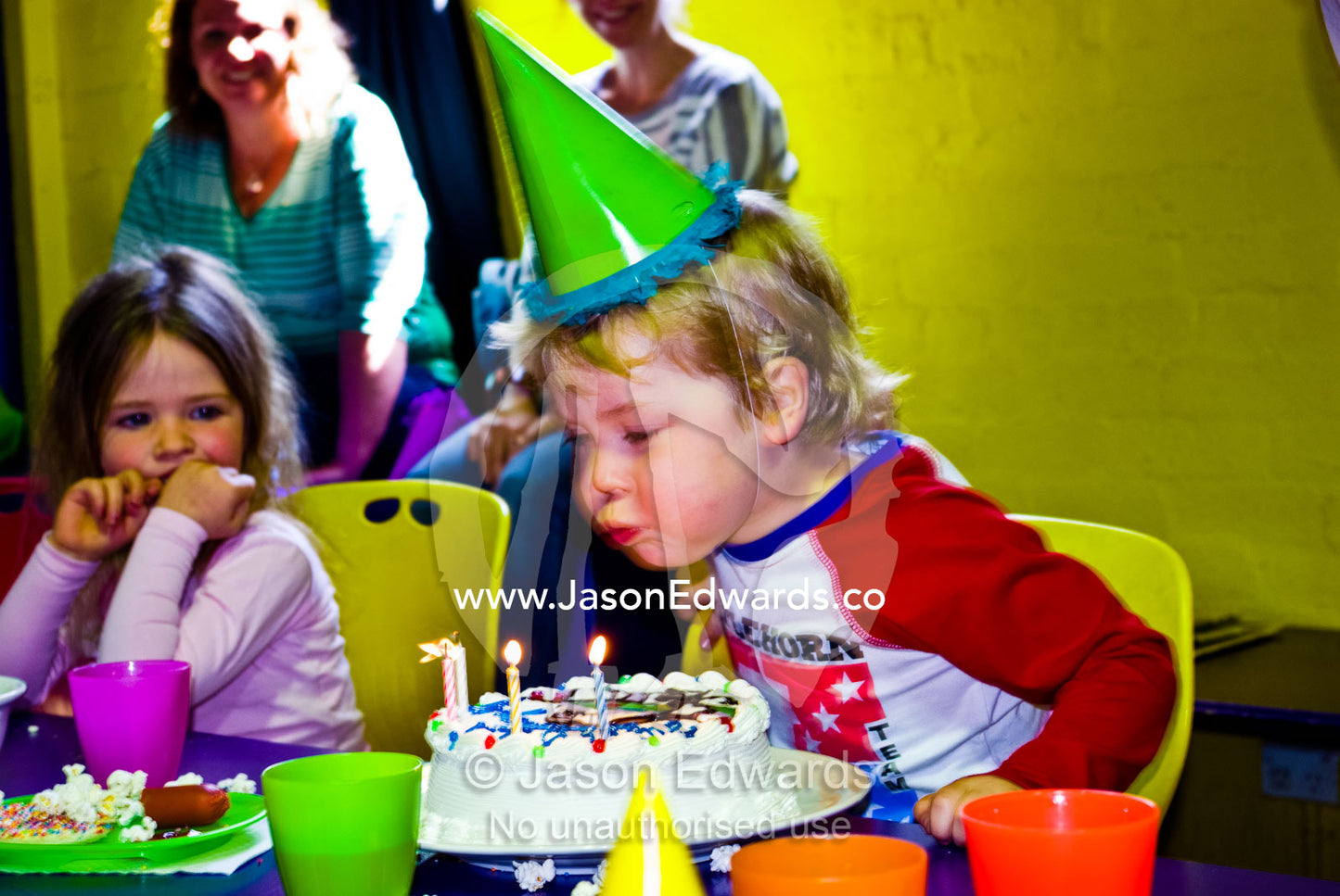A boy blows out candles on his cake at his fourth birthday party. Hawthorn, Melbourne, Victoria, Australia.