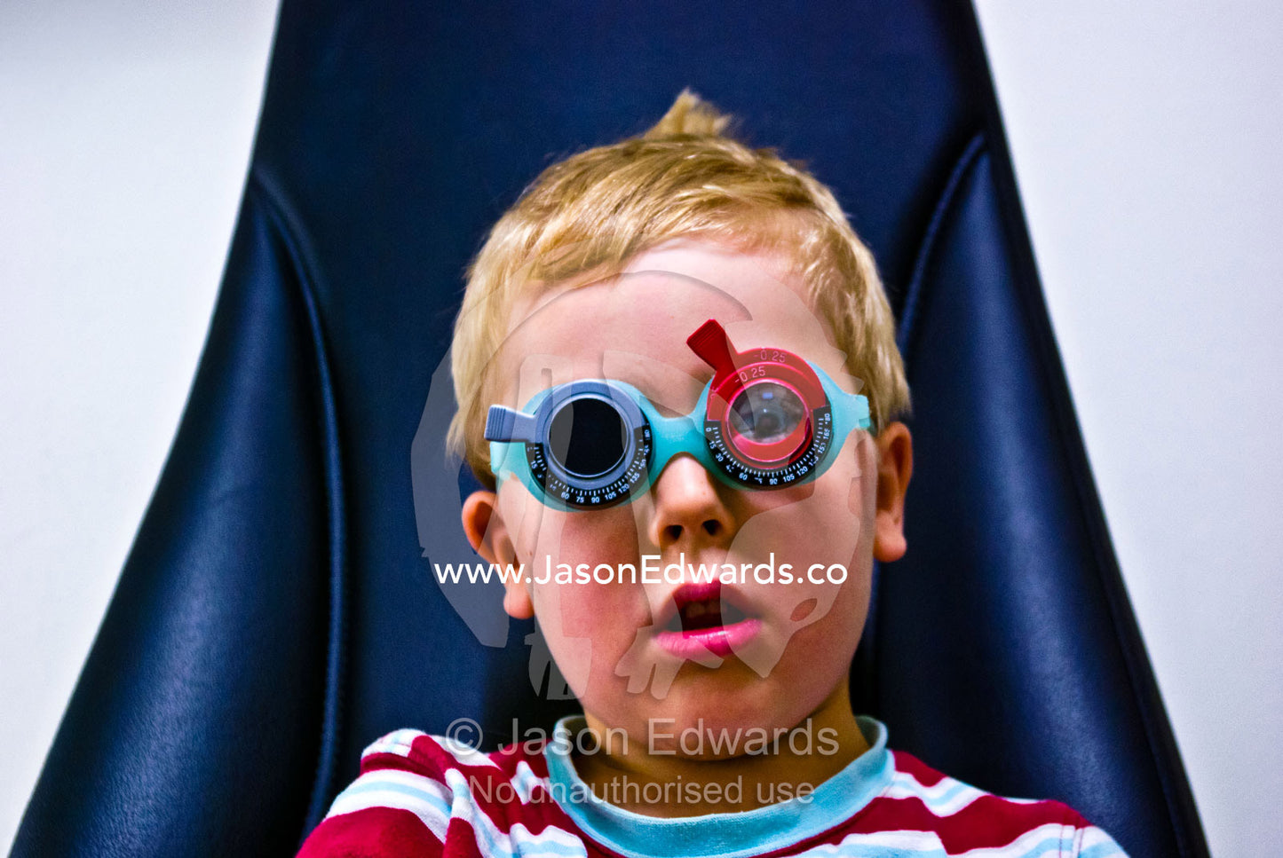 A children's optometrist gives a small boy his first eye examination. Hawthorn, Melbourne, Victoria, Australia.