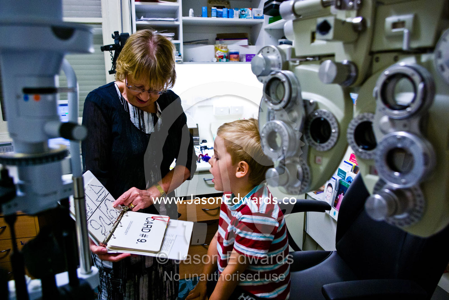 A children's optometrist gives a small boy his first eye examination. Hawthorn, Melbourne, Victoria, Australia.