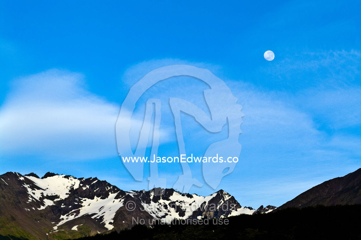 Moonrise in a clear blue sky over snowcapped Andean peaks and ridges. Ushuaia, Martial Mountains, Fuegian Andes, Ushuaia Bay, The Beagle Channel, Tierra del Fuego Archipelago, Straits of Magellan, Tierra del Fuego Province, Patagonia, Argentina.